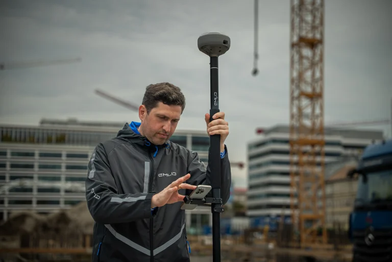 Un technicien prend des points à distance sur un chantier avec le Reach RS4 Pro et la canne Emlid télescopique